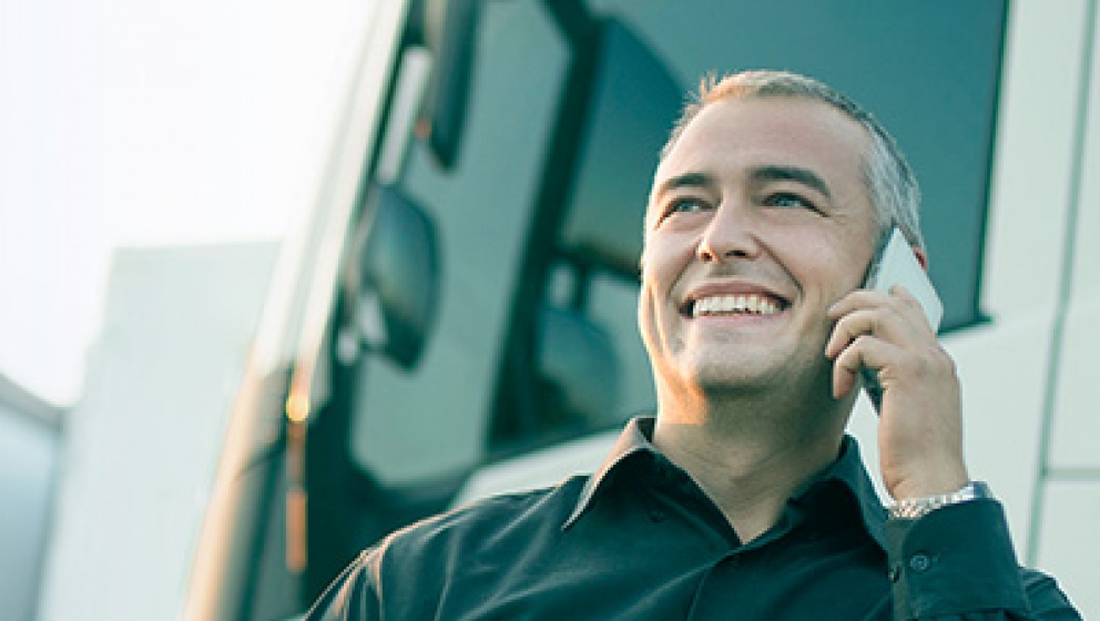man listening to the phone besides a truck